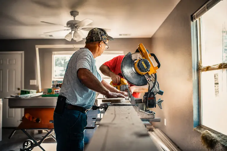 Contractors using a miter saw while framing out a room during a residential renovation